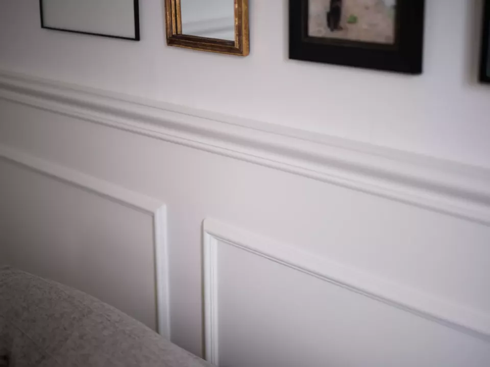 Mur à moulures peint en blanc dans une pièce de réception