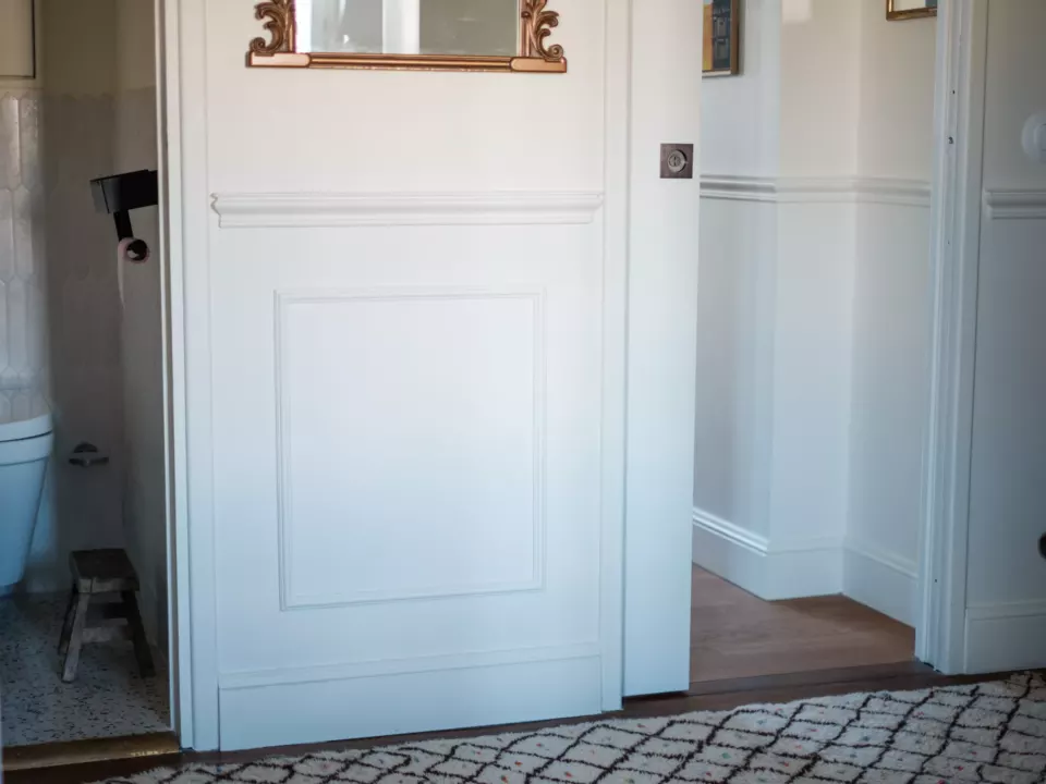 Entrée d’appartement parisien, porte à panneaux et boiseries peintes en blanc