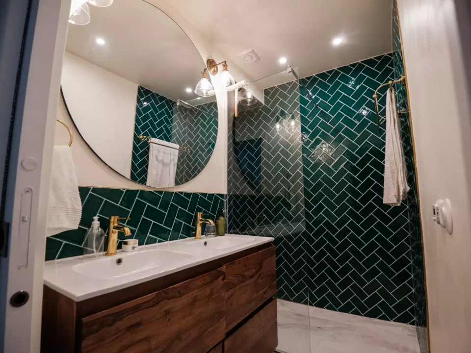 Salle de bain rénovée, faïence verte à chevrons et plafond peint en blanc