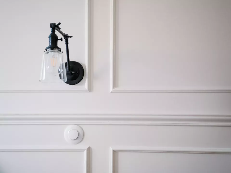 Détail d’un panneau mouluré peint en blanc et applique murale
