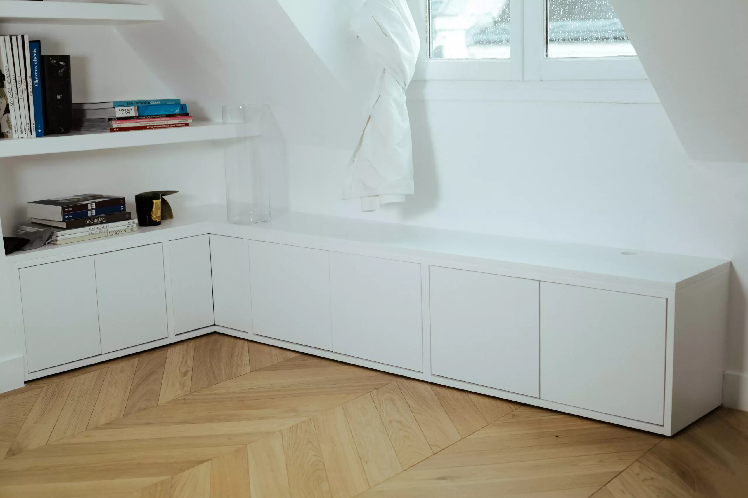 Pièce sous combles aux murs et rangements peints en blanc, parquet point de Hongrie